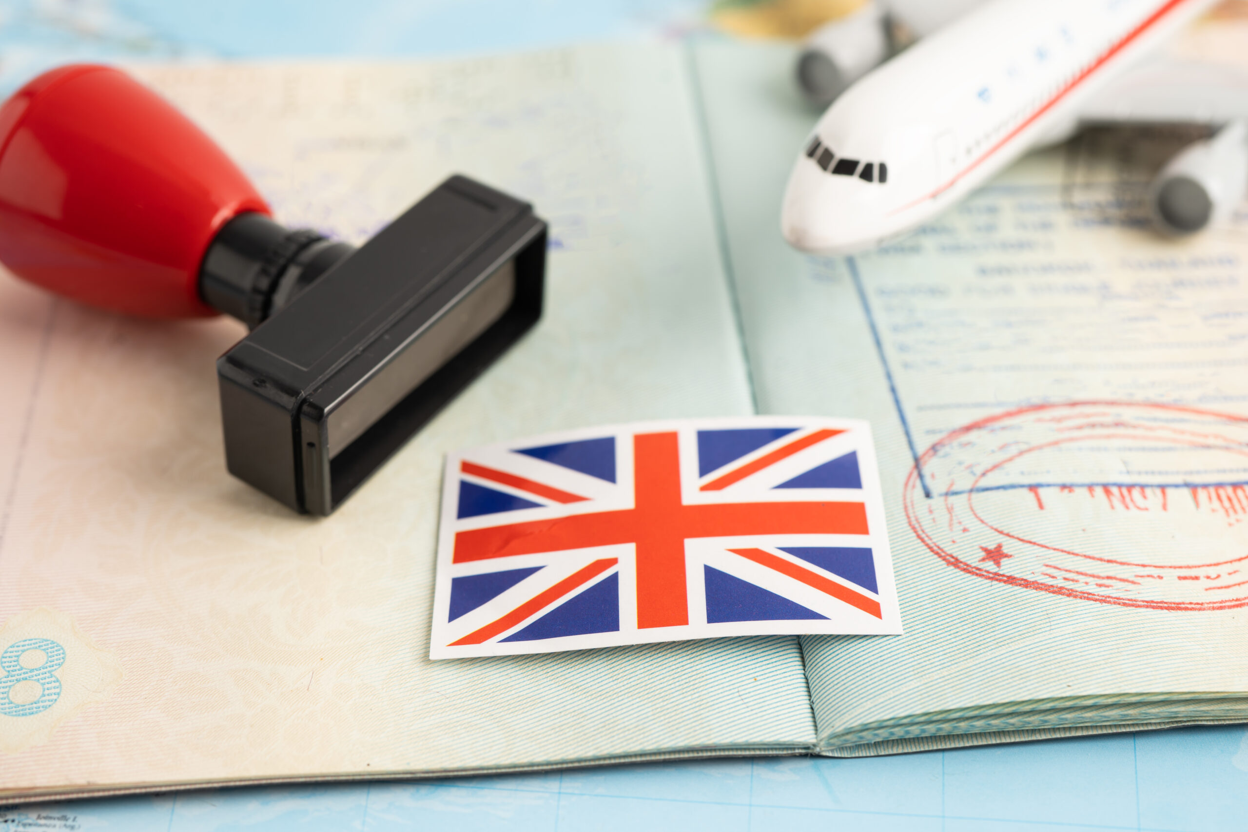 UK passport with approval stamp, Union Jack flag sticker, and toy airplane symbolising the UK Global Talent Visa process.