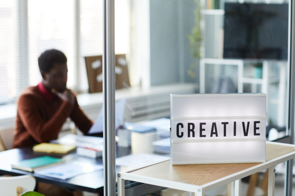 "Creative workspace with a bright sign reading ‘CREATIVE’, symbolising the role of the Global Talent visa in supporting the UK’s creative industries, including film, TV, music, fashion, gaming, and design."
