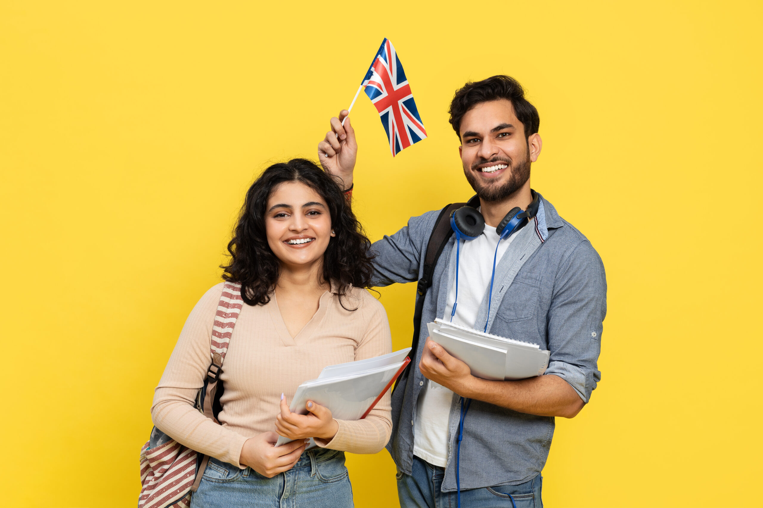 Smiling international students holding notebooks and a UK flag, symbolising opportunities under the UK Global Talent Visa in 2025.