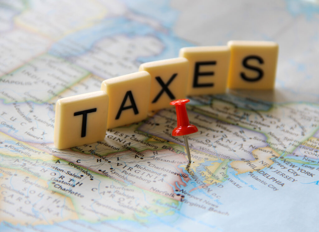 "Scrabble letters spelling TAXES with a red pushpin on a map – symbolising UK tax rules and National Insurance for Global Talent visa holders in 2025."