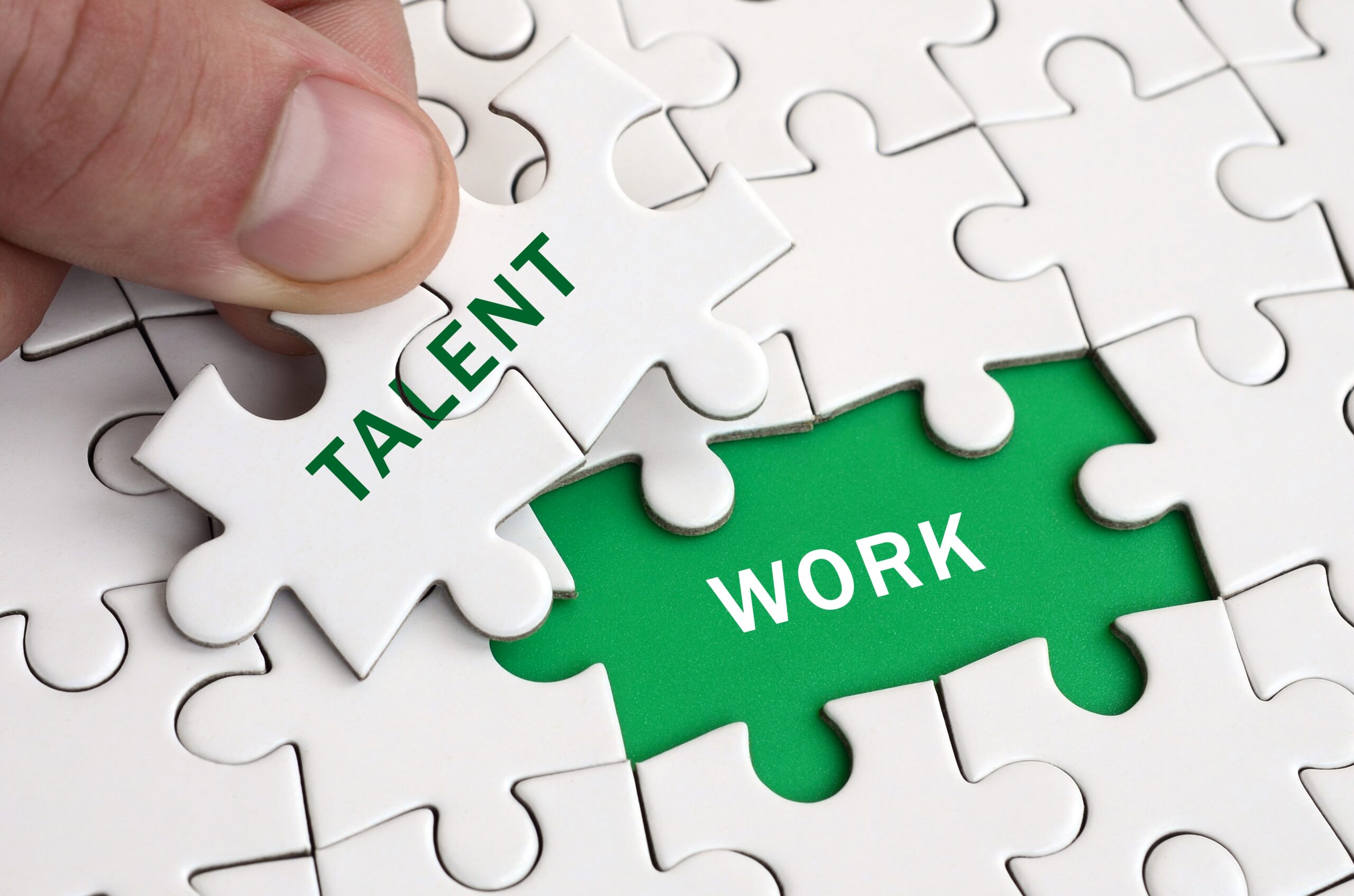 A hand placing the final puzzle piece labelled “TALENT” into a puzzle, completing the connection with a piece labelled “WORK,” symbolising the integration of skilled professionals into the UK workforce in 2025.