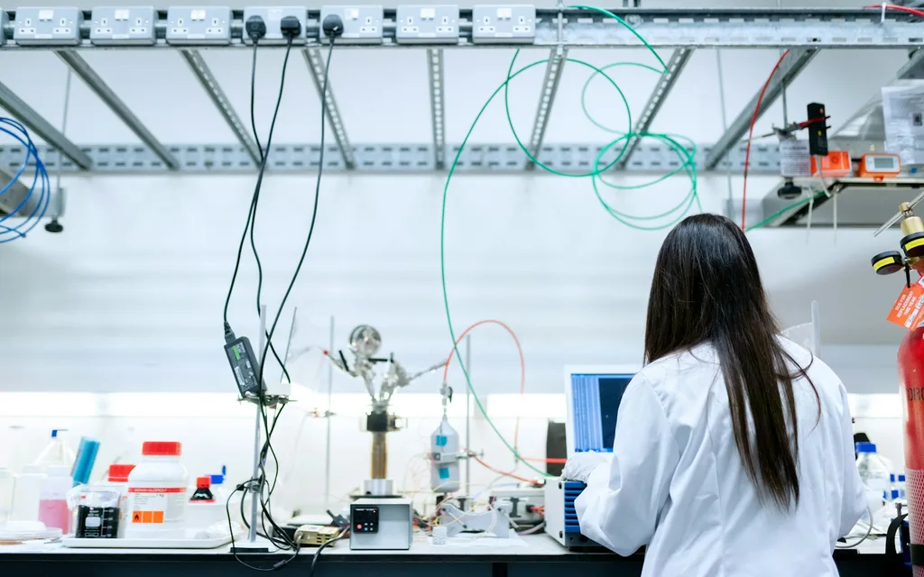 A scientist in a white lab coat using a laptop in a laboratory